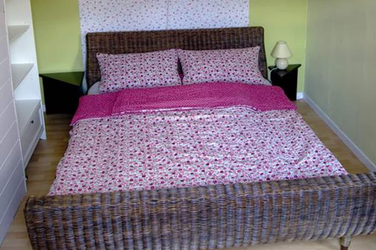 Un dormitorio con cama, mesita de noche, lámpara y aplique de pared.