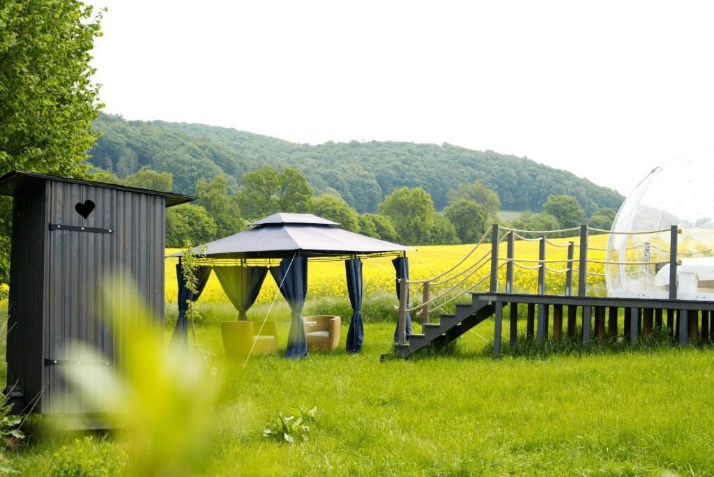 A rustic outdoor setting with a wooden structure, a covered seating area, and a rope bridge.
