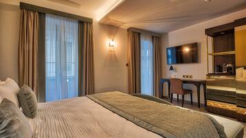 A hotel room with a large bed, a desk, a chair, a TV, and a minibar.