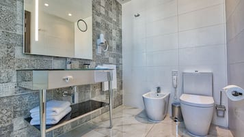 A modern bathroom with a glass vanity, a bidet, and a toilet.