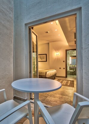A small, well-lit room with a bed, a bathroom, and a dining area with a table and chairs. - Palazzo Rosaria Boutique Hotel (Valletta)