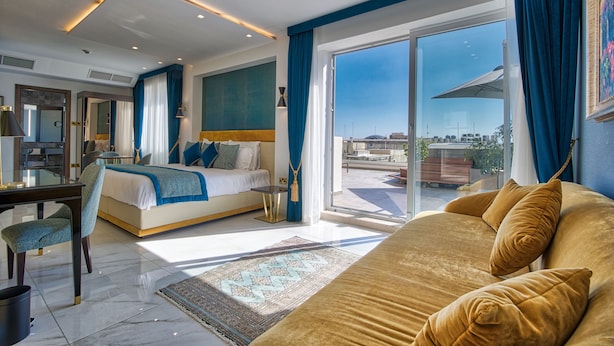 A modern hotel room with a large bed, a desk, and a view of the city.