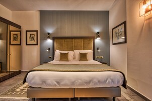 Un dormitorio moderno de hotel con una cama grande, lámparas de noche y cuadros en las paredes.