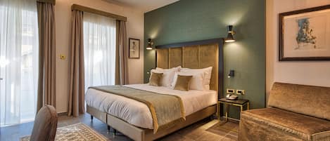 Habitación de hotel con una cama grande, un sofá, un escritorio con teléfono y un cuadro en la pared.