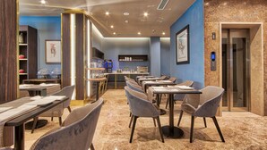 A modern restaurant with marble flooring, contemporary furniture, and a blue accent wall.