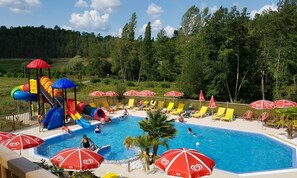 A swimming pool with slides and sun loungers, surrounded by umbrellas. - Camping Le Verdoyant - Mobil-homes (Thenon)