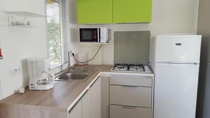 A small kitchen with a sink, a microwave, a stove, and a refrigerator.