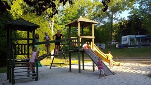 A playground with a wooden structure, slides, and a fenced area.
