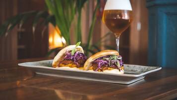 A plate with two tacos and a glass of beer on a wooden table.