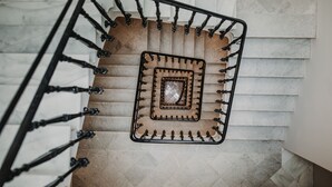 Una escalera de caracol con barandilla de metal y un azulejo decorativo cuadrado en el centro.