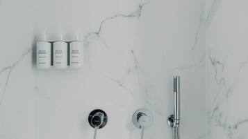A bathroom with a marble wall, a shower, and three bottles of Helen Berger products.
