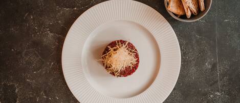A plate with a meatball and grated cheese on a textured surface.