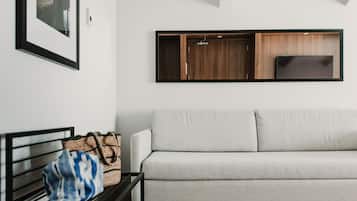 A modern living room with a sofa, a framed picture on the wall, and a wooden cabinet with a television.