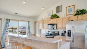 A modern kitchen with a central island, stainless steel appliances, and wooden bar stools.
