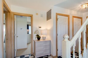 A hallway with a checkered floor, white walls, and a staircase with wooden railings.
