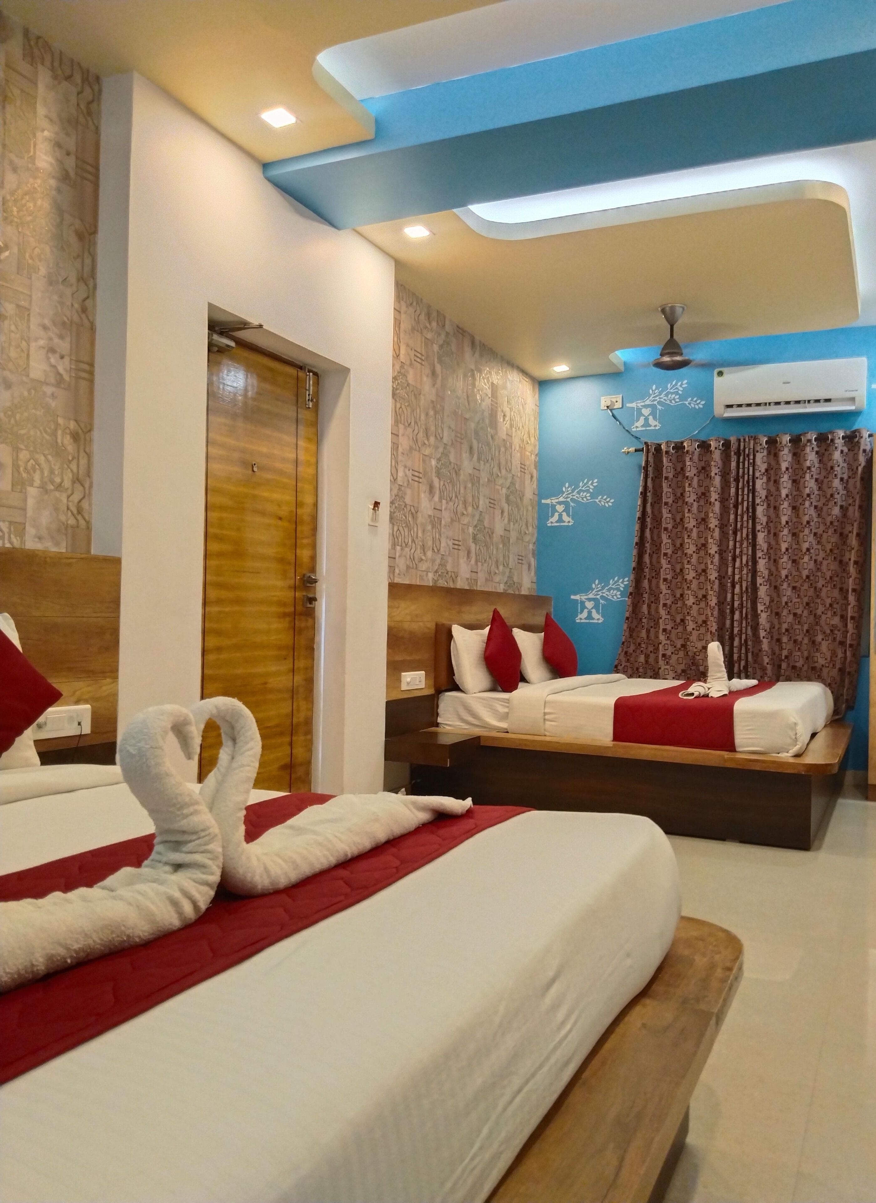 Habitación de hotel con dos camas, cabecero de madera, aire acondicionado de pared y ventilador de techo.