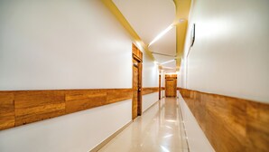 A long, narrow hallway with wooden paneling on the walls and a shiny tiled floor. - Hotel SDM Golden Tower (Rameshwaram)