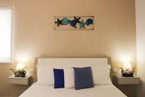 Una habitación de hotel con una cama, dos mesitas de noche y un adorno en la pared.