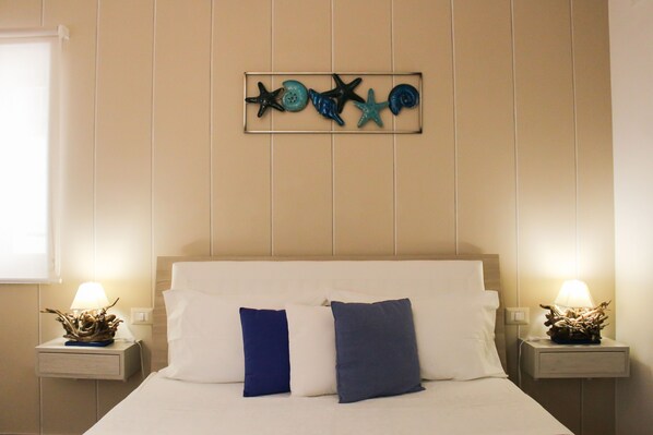 A hotel room with a bed, two nightstands, and a wall decoration. - B&B Dimora del Pescatore Cefalù (Cefalù)