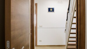 A wooden door leading to a hallway with a wooden floor, a staircase, and a ceiling-mounted ship model. - B&B Dimora del Pescatore Cefalù (Cefalù)
