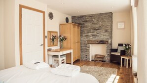 Un dormitorio con cama, escritorio, armario, chimenea de piedra y una cesta de mimbre.