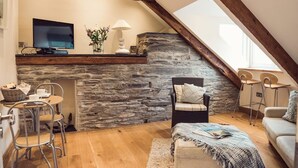 Un dormitorio tipo loft acogedor con chimenea de piedra, un televisor y un comedor con sillas y una mesa.