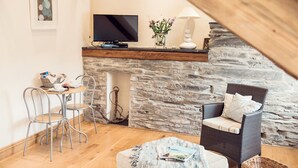 Una sala de estar acogedora con chimenea de piedra, un televisor y un sillón de mimbre.