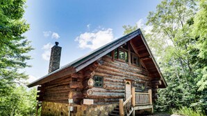 A log cabin with a stone foundation, wooden exterior, and a chimney. - Infinite Views - 2BR/New Hot Tub/New Firepit/Grill/Sleeps 6 (Gatlinburg)