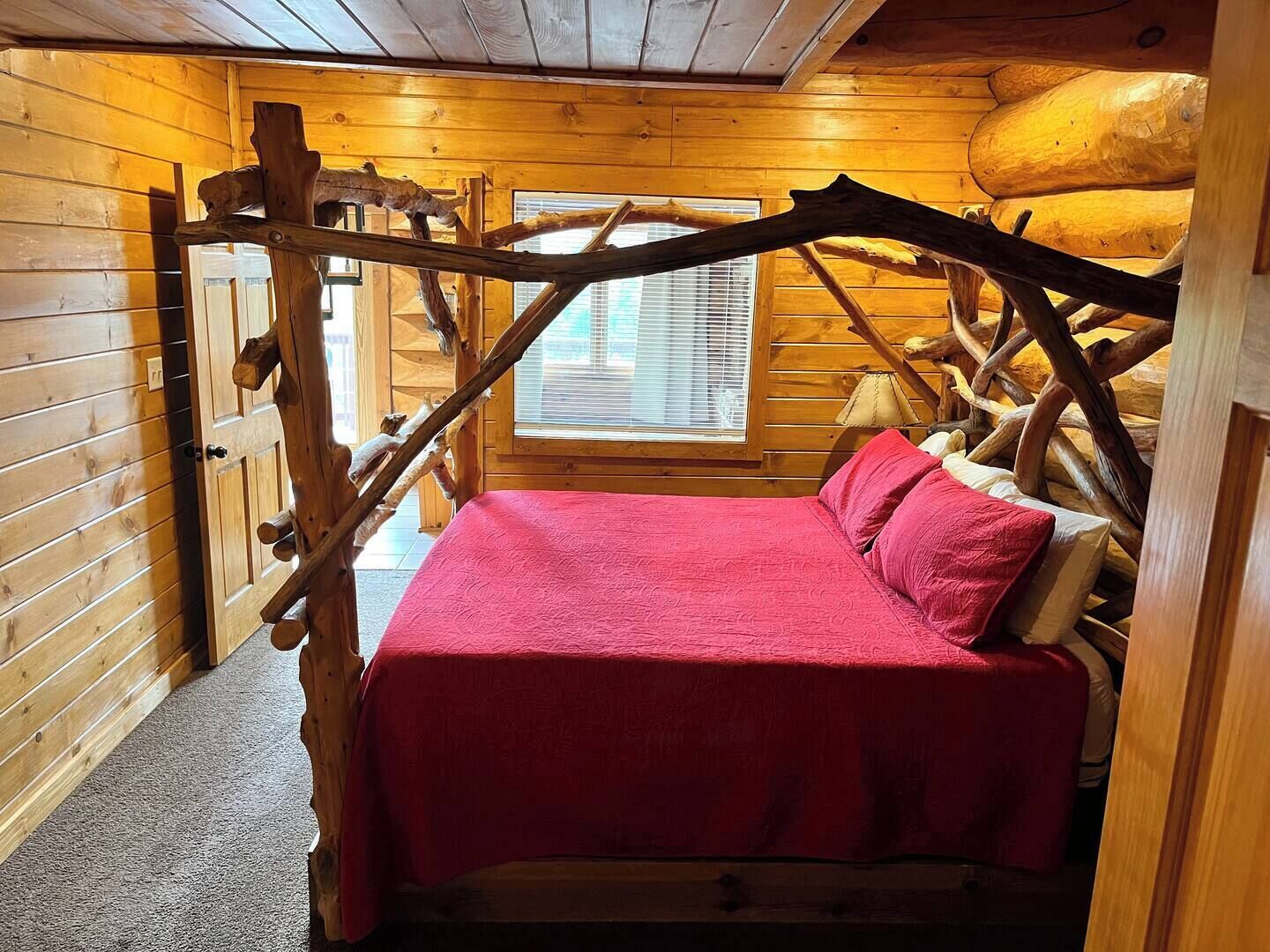 Une chambre confortable dans un chalet en rondins, avec un lit, des poutres en bois et une fenêtre.