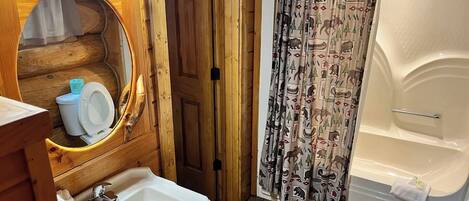 Et badeværelse i en træhytte med vask, toilet og badekar.