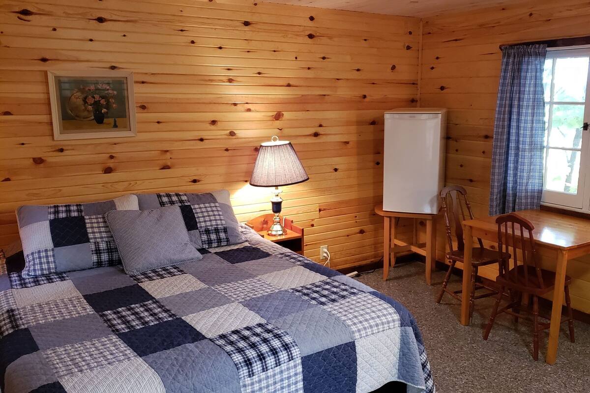 A cozy cabin room with a bed, a desk, and a chair.
