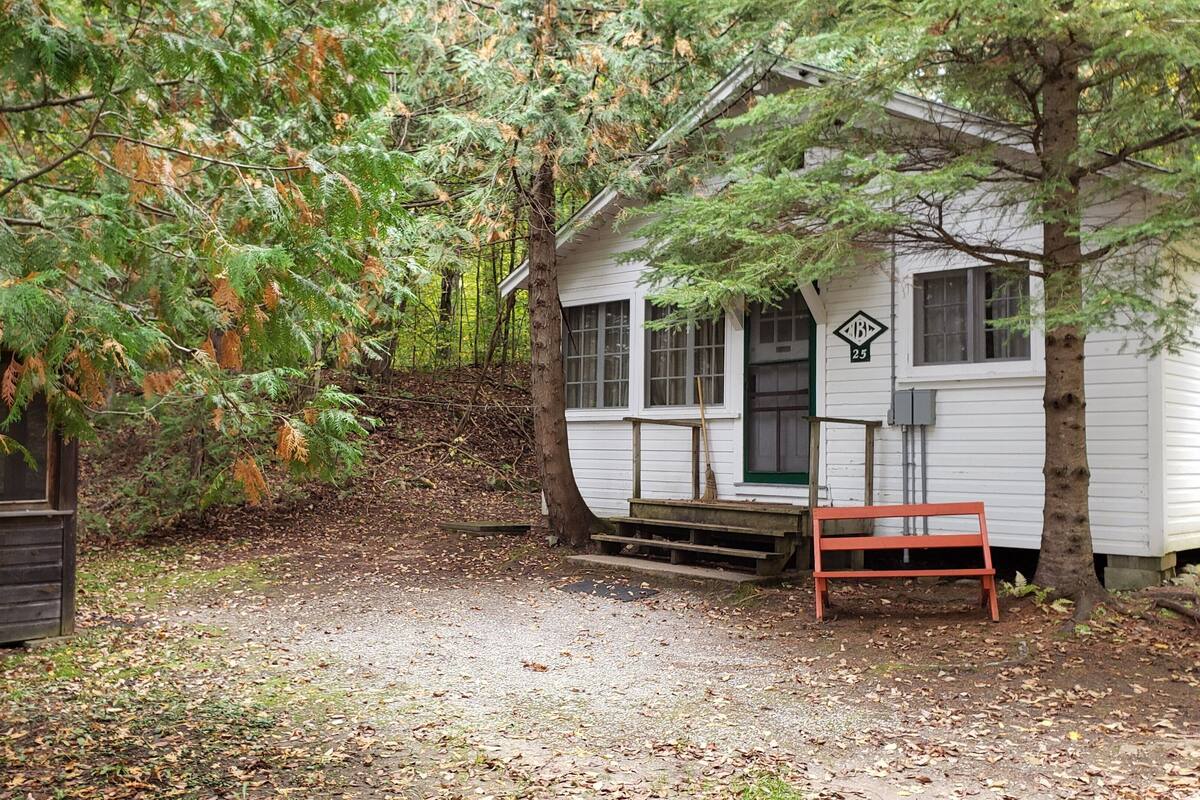 A cabin with a porch, a bench, and a small staircase leading to the entrance.