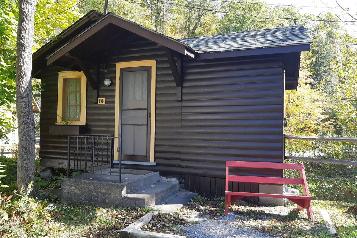 A small cabin with a front door, a window, and a red bench outside.