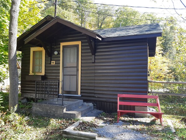 A small cabin with a front door, a window, and a red bench outside. - Miners Bay Lodge (Minden Hills)