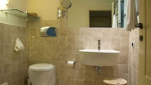 Un baño con inodoro, lavamanos y un taburete pequeño.