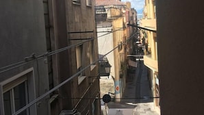 Una calle estrecha flanqueada por edificios, con balcones y un cielo despejado.