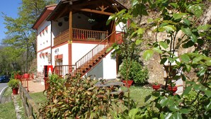 A two-story building with a balcony, a staircase, and potted plants. - Casa Rural Priena (Cangas de Onis)