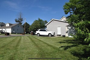Two homes share a lawn with a shaded area under a large tree.