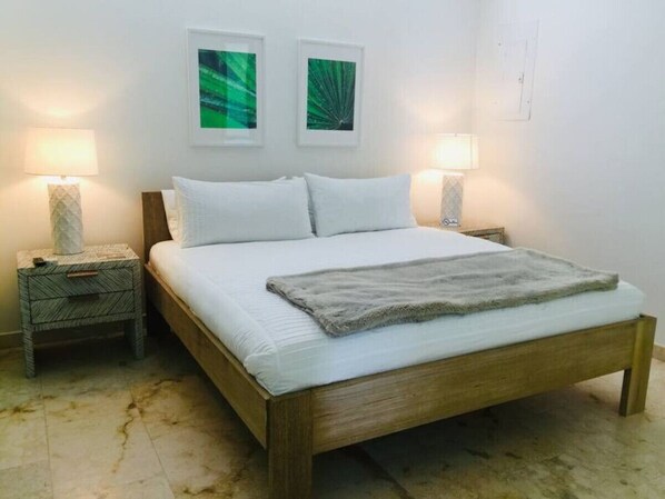 Une chambre à coucher avec un lit en bois, deux tables de chevet, deux lampes fixées au mur et deux tableaux encadrés.