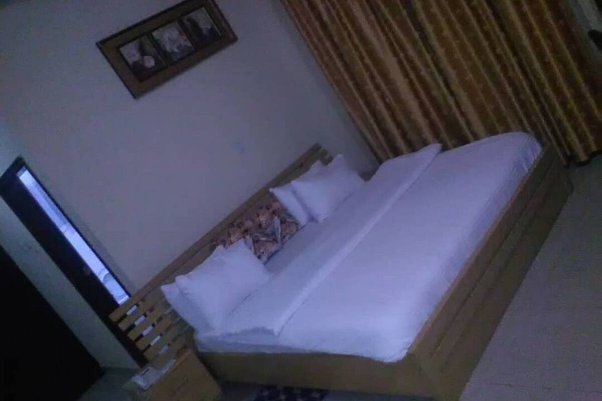 A single bed with white bedding, a wooden headboard, and a small bedside table with a lamp.