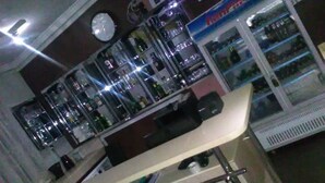 A bar area with a counter, stools, and shelves stocked with bottles. - Jewima Hotel (Accra)