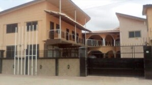 A multi-story building with a balcony on the second floor and a gated entrance. - Jewima Hotel (Accra)