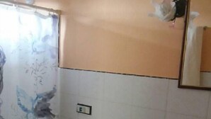 A bathroom with a toilet, sink, and a wall with a partial painting. - Hostal En Casa (Bayamo)