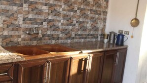 A kitchen with a stone backsplash, wooden cabinets, and a stainless steel sink. - Edom camp (Dana)