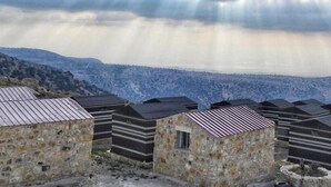A row of stone buildings with metal roofs, set against a mountainous backdrop. - Edom camp (Dana)