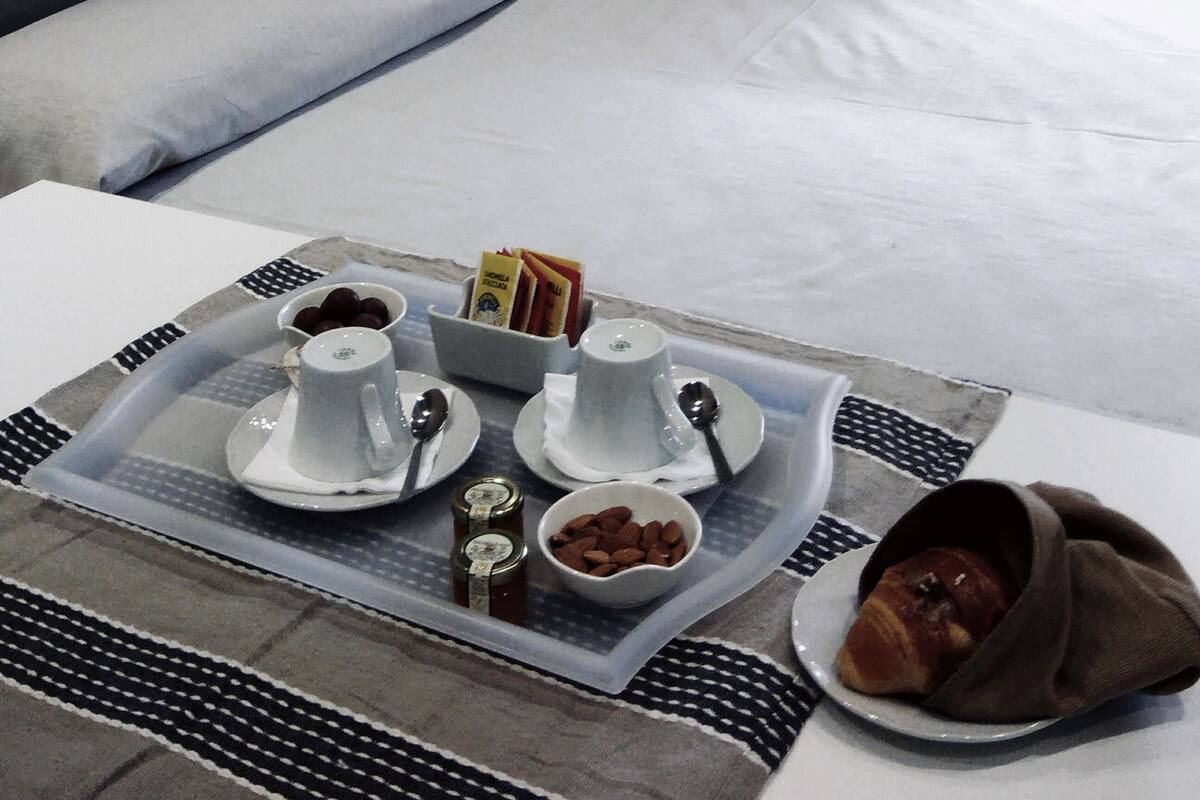 A neatly made bed with a tray of breakfast items including croissants, jams, and coffee.