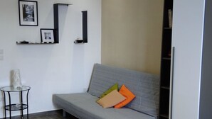 A modern, well-lit room with a grey sofa, a small round table, and a bed. - B&B Napoli Culture (Naples)