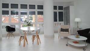 A modern living room with a round table, two chairs, a sofa, a lamp, and a coffee table.