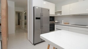 A modern kitchen with white cabinetry, stainless steel appliances, and a clean, minimalist design.