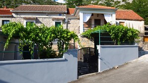 A stone building with a tiled roof, a gated entrance, and a view of a mountainous landscape. - Holiday Home Ante is set in Starigrad Paklenica. (Starigrad Paklenica)